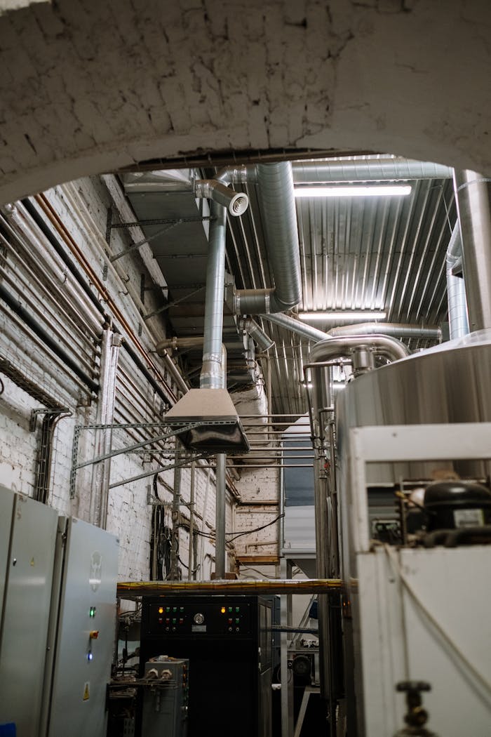 Stainless steel equipment inside a modern industrial brewery with intricate piping and machinery.